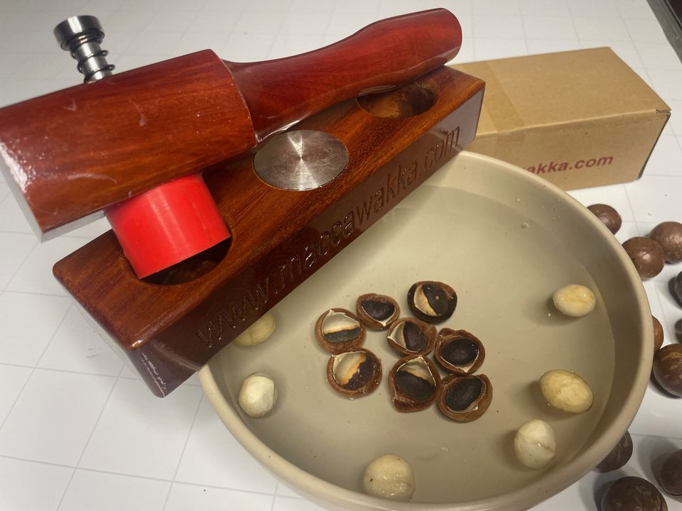 The MaccaWakka macadamia nut cracker: stained hardwood base and hammer, stainless steel strike plate and red silicone cup, with a bowl of freshly cracked macadamias