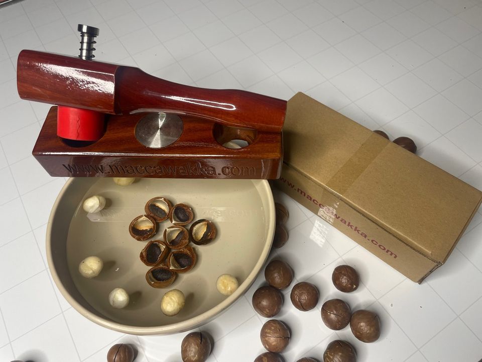 MaccaWakka nut cracker beside a bowl of freshly cracked macadamia kernels in their split shells