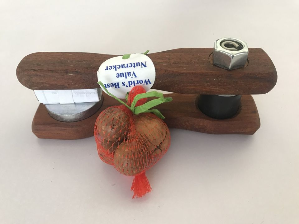 The Nut Buster timber nut cracker with its steel nut on top and a bag of macadamias